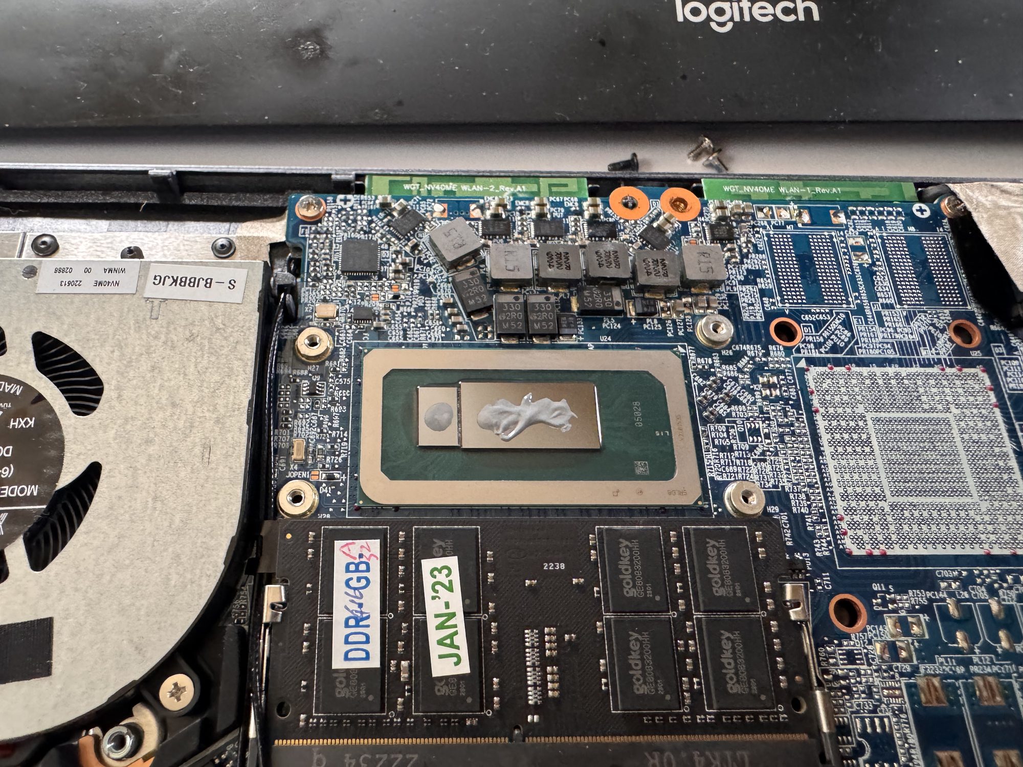 Close-up of the CPU with a fresh blob of white thermal paste applied, not yet spread, ready for the heat sink to go back on.